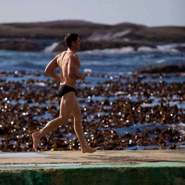 Young man running on beach after Pilates